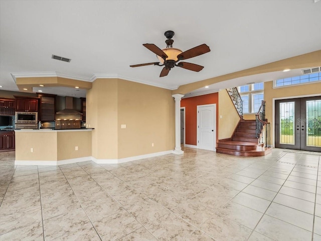 unfurnished living room with french doors, visible vents, decorative columns, and stairs