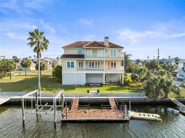 exterior space with a water view, a lawn, boat lift, and a balcony