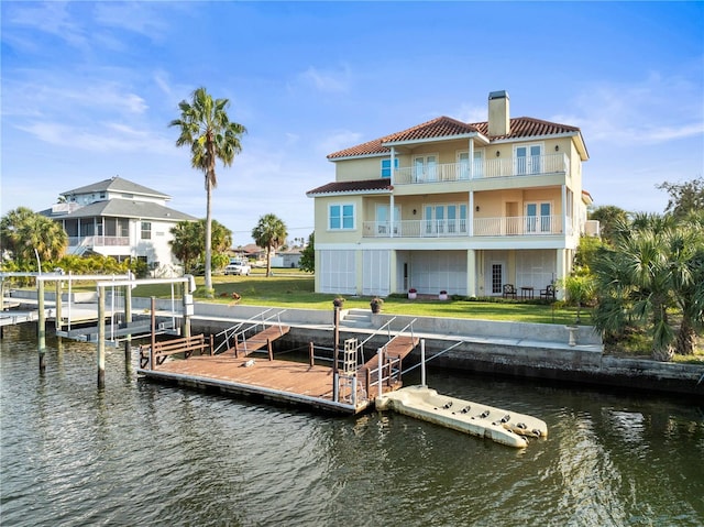 dock area featuring a water view, a yard, boat lift, and a balcony