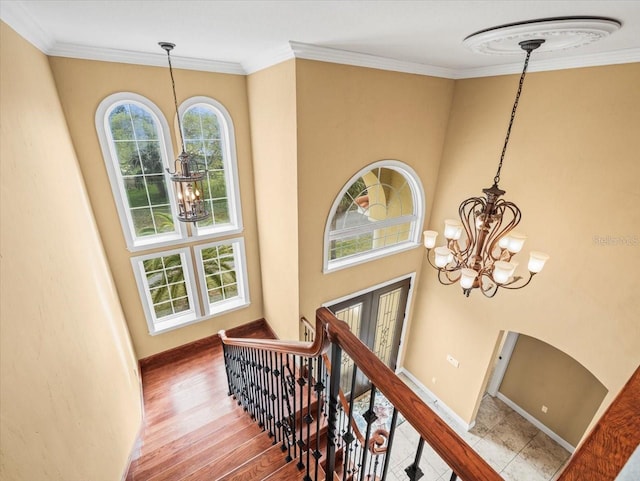 staircase with a chandelier, baseboards, wood finished floors, and crown molding