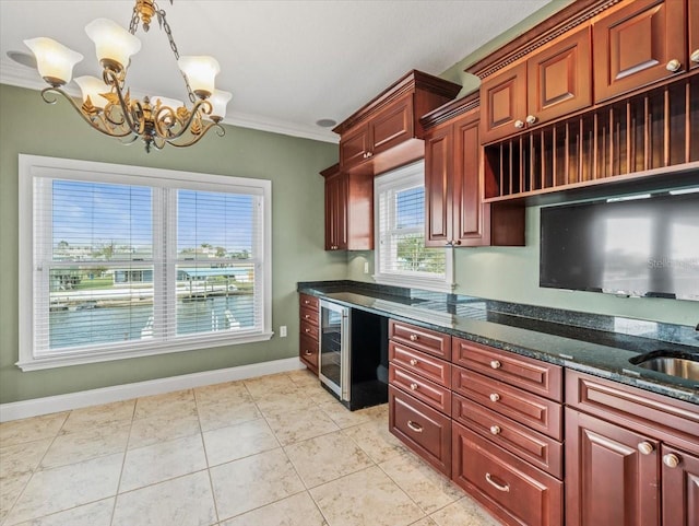 kitchen featuring wine cooler, crown molding, hanging light fixtures, dark stone countertops, and baseboards