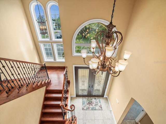 foyer with french doors, stairway, baseboards, and an inviting chandelier