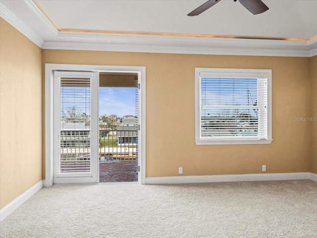 carpeted empty room featuring a ceiling fan, baseboards, and crown molding