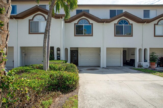 view of property featuring driveway, an attached garage, and stucco siding