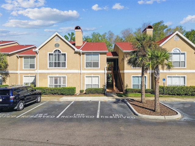 view of building exterior with stairs and uncovered parking