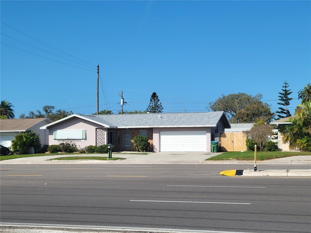 ranch-style home featuring a garage, driveway, and fence