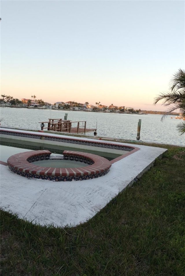 view of dock with an in ground hot tub and a water view