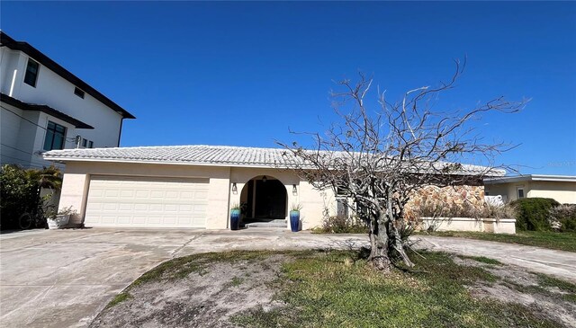 view of front of property featuring a tiled roof, a garage, driveway, and stucco siding