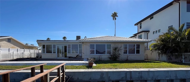 rear view of house featuring a yard, a sunroom, fence private yard, and stucco siding