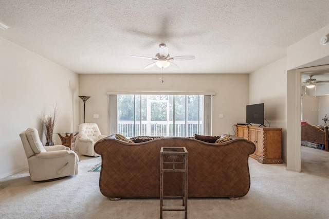 living room with a ceiling fan, light colored carpet, and a textured ceiling