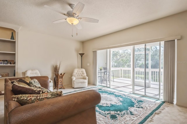 living area with a textured ceiling, ceiling fan, and carpet flooring