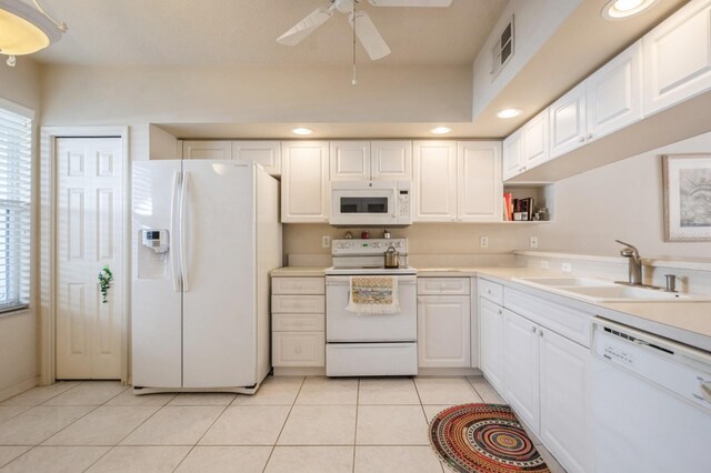 kitchen with white appliances, white cabinets, a sink, and light tile patterned flooring