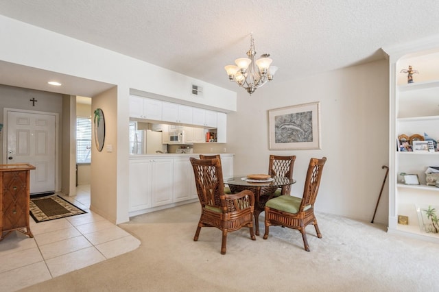 dining area with light carpet, light tile patterned floors, visible vents, an inviting chandelier, and a textured ceiling