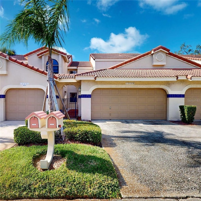 mediterranean / spanish-style house with an attached garage, driveway, a gate, and stucco siding