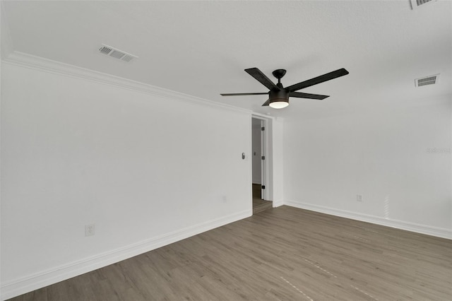 unfurnished room featuring a ceiling fan, baseboards, visible vents, and wood finished floors