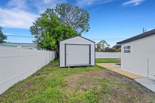 view of yard featuring an outbuilding, a fenced backyard, and a storage unit