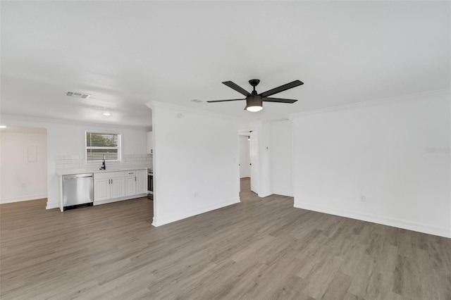 unfurnished living room featuring ceiling fan, a sink, visible vents, light wood-style floors, and crown molding