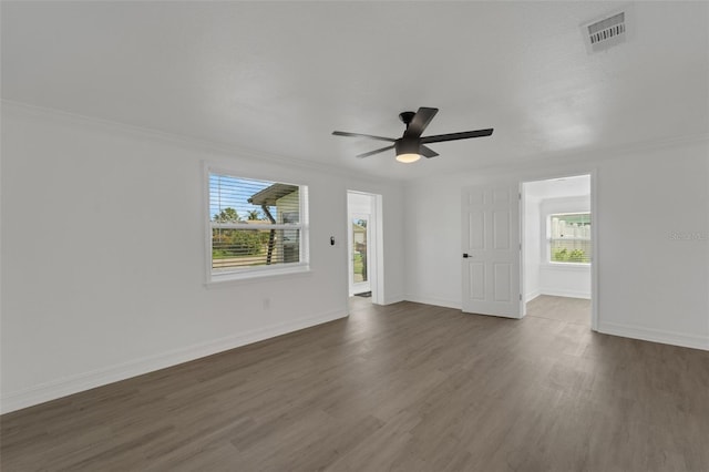 interior space featuring a ceiling fan, baseboards, visible vents, dark wood finished floors, and crown molding