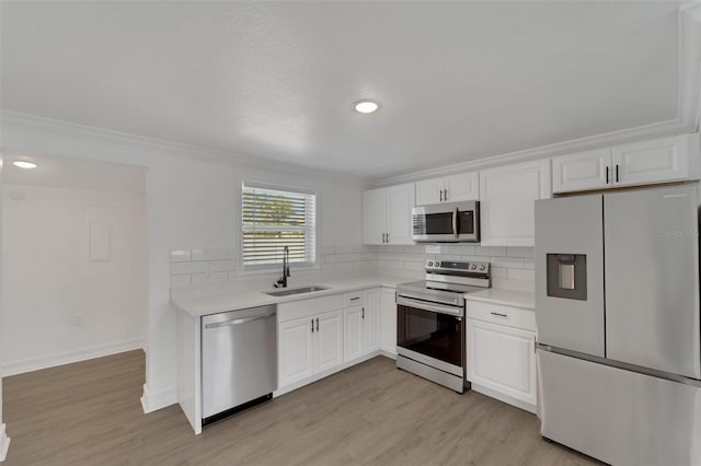 kitchen with light wood-type flooring, appliances with stainless steel finishes, decorative backsplash, and a sink