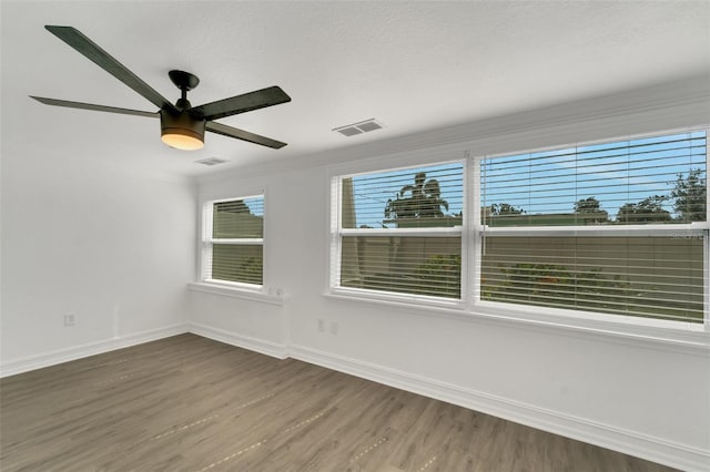 empty room with visible vents, ceiling fan, a textured ceiling, wood finished floors, and baseboards