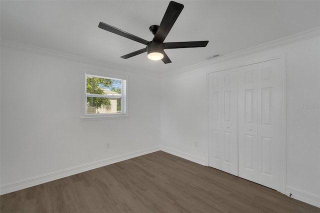 unfurnished bedroom featuring dark wood-style floors, visible vents, baseboards, and crown molding