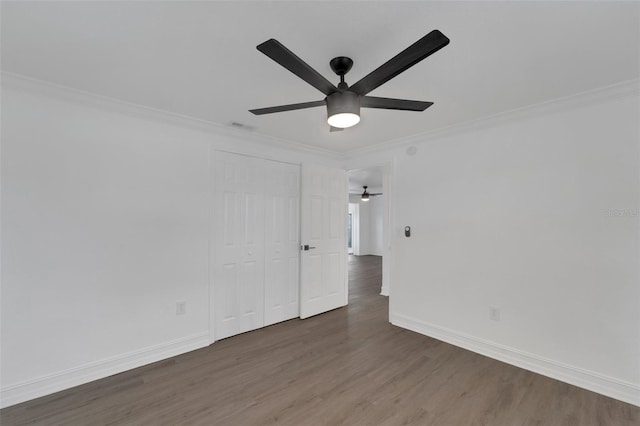 empty room with baseboards, visible vents, crown molding, and wood finished floors