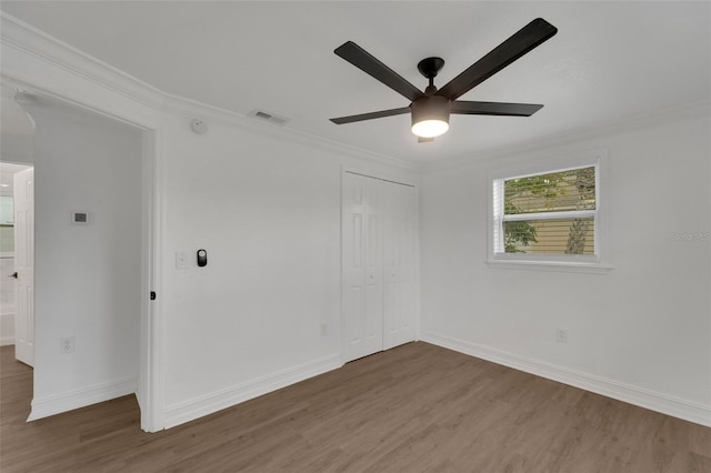 unfurnished room featuring baseboards, visible vents, crown molding, and wood finished floors