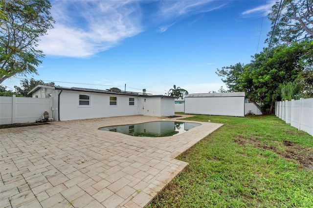 back of house with a patio, a fenced backyard, an outdoor structure, a lawn, and stucco siding