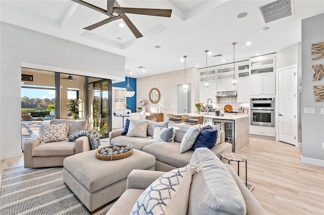 living room featuring coffered ceiling, visible vents, and ceiling fan