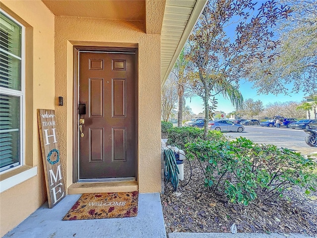 doorway to property with uncovered parking and stucco siding