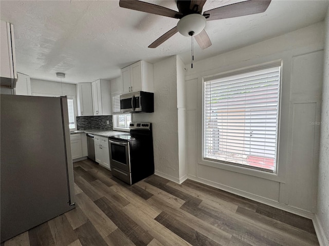 kitchen featuring dark wood finished floors, stainless steel appliances, tasteful backsplash, white cabinetry, and a textured ceiling