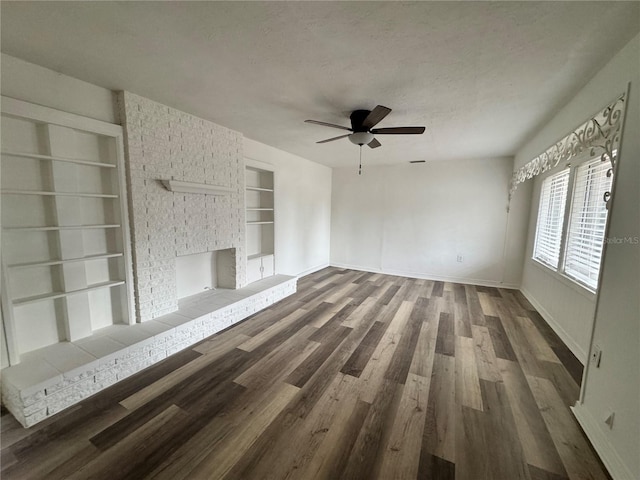 unfurnished living room featuring built in features, a fireplace, a textured ceiling, wood finished floors, and baseboards