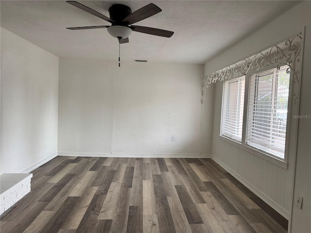 empty room with a ceiling fan, visible vents, baseboards, and wood finished floors