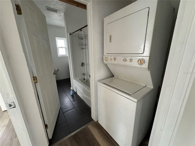 washroom with visible vents, stacked washer / dryer, a textured ceiling, wood finished floors, and laundry area