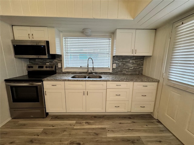 kitchen featuring stainless steel appliances, white cabinetry, a sink, and wood finished floors