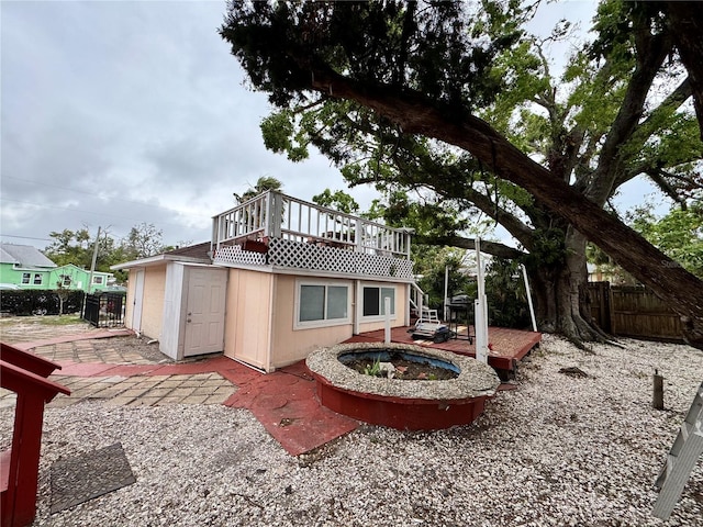 back of house with a patio, an outdoor fire pit, fence, and a wooden deck