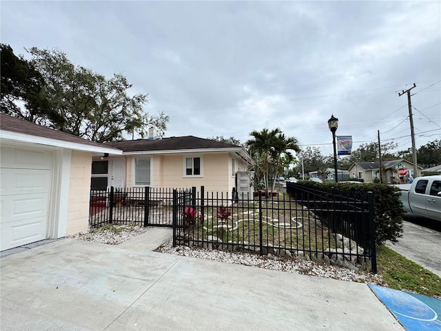 view of front facade with a fenced front yard, concrete block siding, and a garage