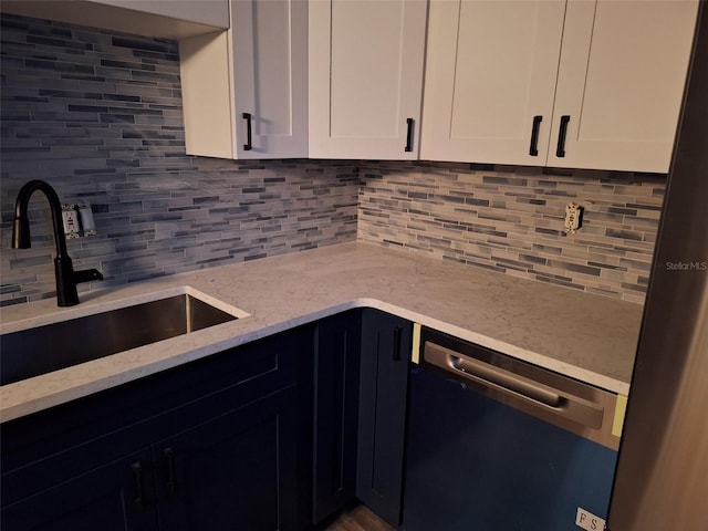 kitchen featuring white cabinetry, appliances with stainless steel finishes, decorative backsplash, and a sink