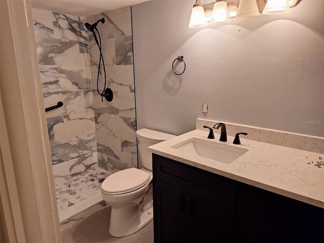 full bathroom with toilet, tiled shower, and vanity