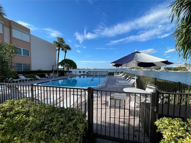 pool featuring a water view, fence, and a patio