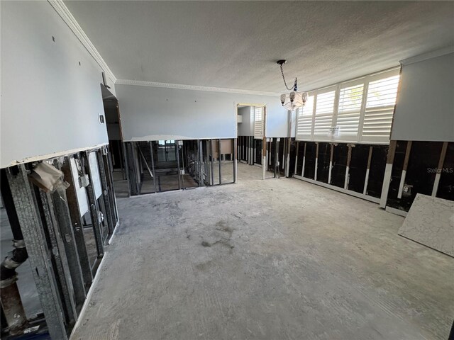 unfurnished living room with a textured ceiling, ornamental molding, and a notable chandelier