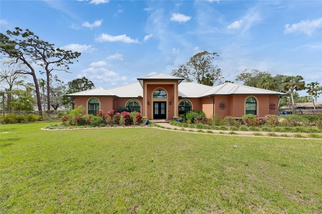 mediterranean / spanish house with metal roof, a standing seam roof, a front lawn, and stucco siding