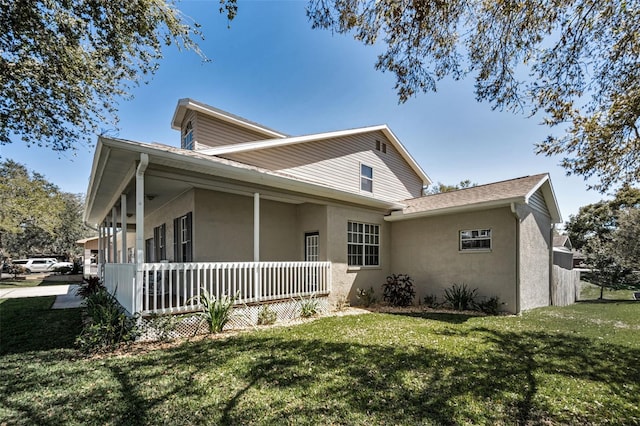 view of front facade featuring stucco siding, a porch, and a front yard