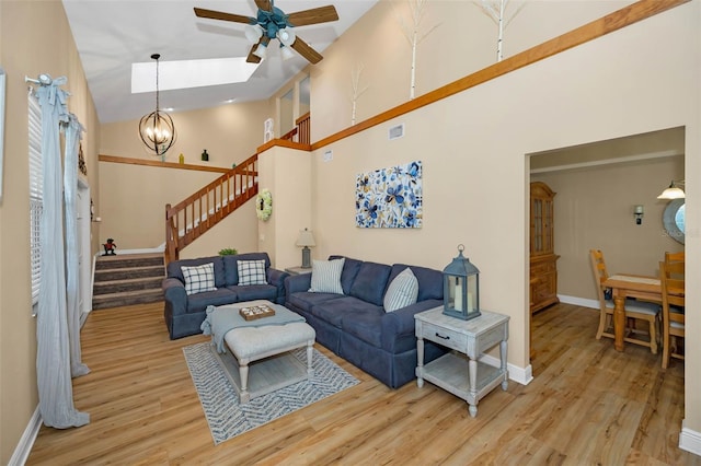 living area featuring wood finished floors, visible vents, baseboards, a high ceiling, and stairs