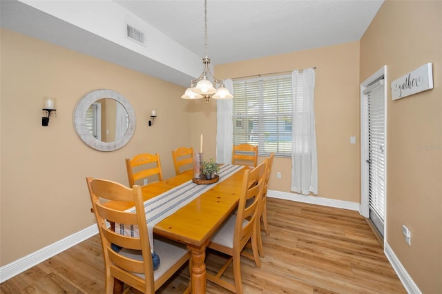 dining area with visible vents, baseboards, light wood-style floors, and a notable chandelier