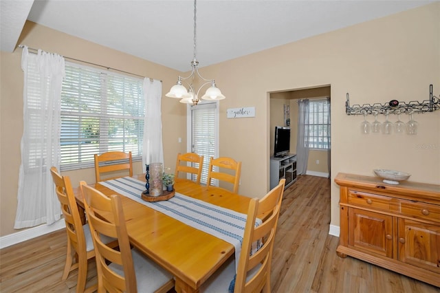 dining room with light wood-style flooring, baseboards, and a chandelier