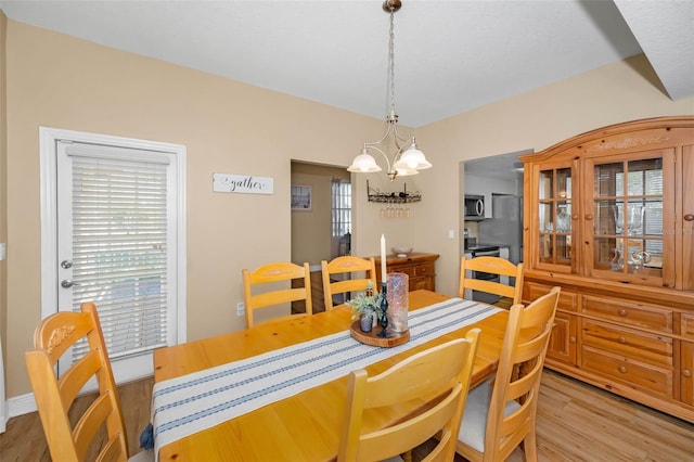 dining area featuring a notable chandelier, plenty of natural light, and light wood-type flooring