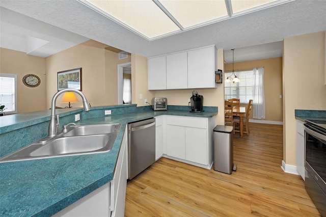 kitchen with white cabinets, appliances with stainless steel finishes, light wood-style flooring, and a sink