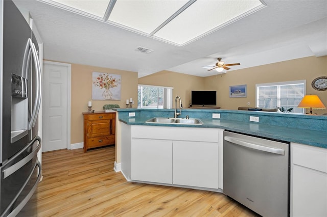 kitchen featuring visible vents, appliances with stainless steel finishes, light wood-style floors, white cabinets, and a sink