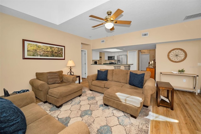 living area with visible vents, light wood-style floors, and a ceiling fan